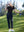 Model in black women's performance solid polo holding a golf club outdoors