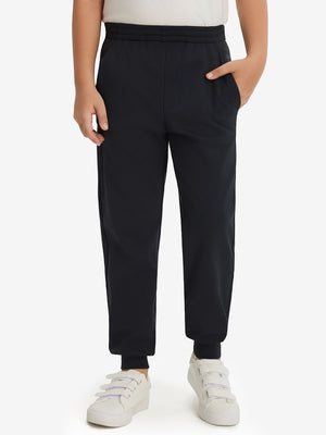 Model wearing black fleece stretch water resistant boys joggers, front view showing lower body and pants.
