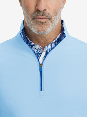Close-up from nose to chest, showing collar and zipper detail of the light blue golf pullover.