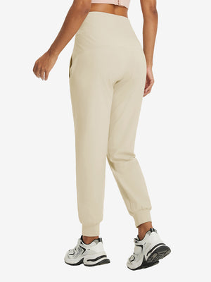 Model wearing women's stretch fleece lined water resistant joggers in light khaki, showing the back lower body view.