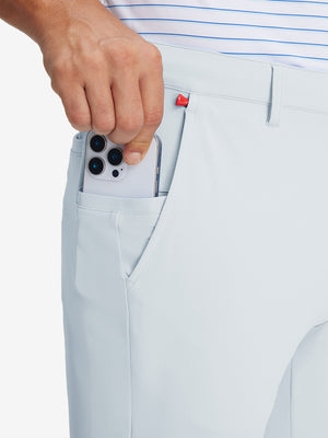 Hand placing an iPhone into pocket of soft lightweight casual golf pants with 5 pockets in misty grey.