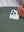 Close detail of hand placing phone into back pocket of lightweight moisture wicking dress pants in slate green.