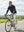 Model riding a bicycle on the road outdoors, wearing dry fit stretchy sweatshirts hoodies in dark grey