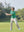 The model is wearing Boys Stretch Fleece Lined Casual Golf Pants in LIGHT KHAKI while playing golf on the golf course.