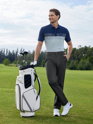 Model leaning beside golf bag on course in Water resistant everyday pants, relaxed dark grey look